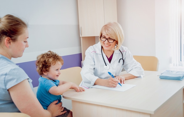 Doctor amable pediatra con niño paciente en clínica