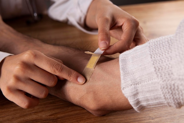Doctor aplicando cinta adhesiva en la mano del hombre