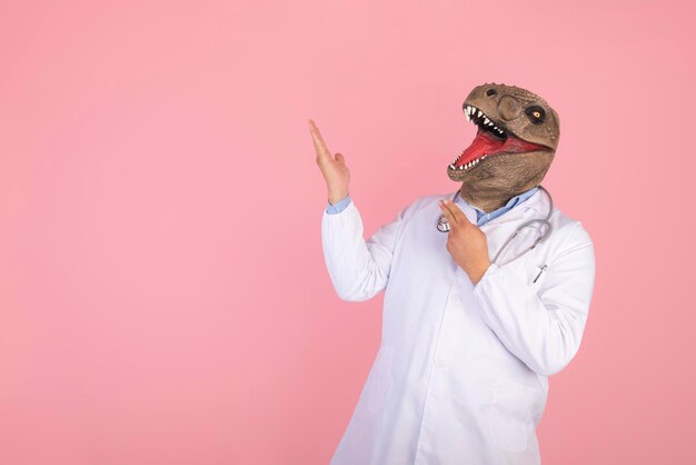 Doctor apuntando al espacio vacío sobre fondo rosa aislado