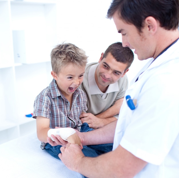 El doctor arrolla el brazo de un niño que está gritando