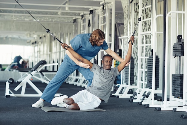 Doctor ayudando al paciente a hacer ejercicio en el gimnasio