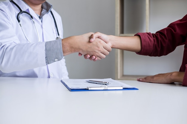 Foto doctor en bata blanca agitando la mano con el paciente después de recomendar el tratamiento con éxito