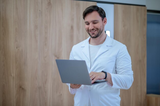 Doctor en una bata de laboratorio con una computadora portátil que tiene una sesión en línea