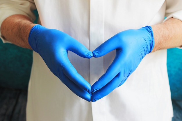 Doctor en bata de laboratorio médico muestra forma de corazón de tarjeta