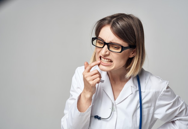 Doctor en una bata médica con un estetoscopio alrededor de su cuello mirada perpleja fondo gris