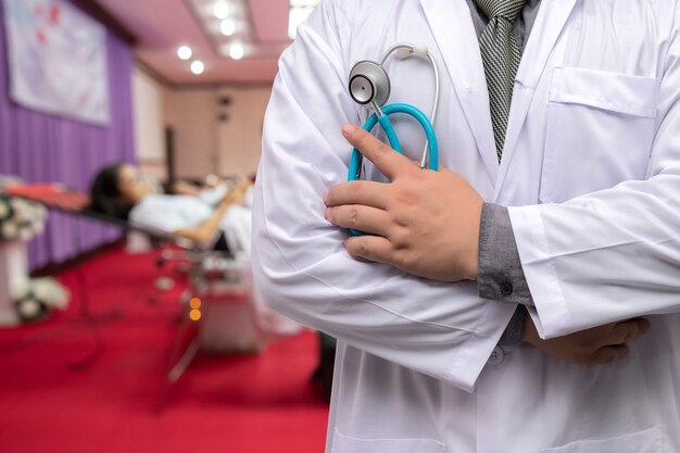 Foto doctor en bata de uniforme con estetoscopio de pie en la sala de donación de sangre