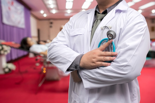 Doctor en bata de uniforme con estetoscopio de pie en la sala de donación de sangre