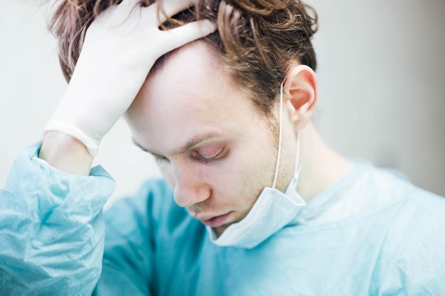 doctor cansado sosteniendo su cabeza agotamiento de cirujano profesional