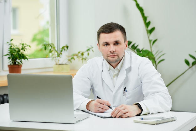 Doctor caucásico en una bata blanca haciendo papeleo