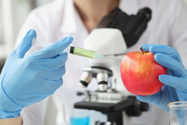 Doctor científico hace inyección en manzana en concepto de tratamiento con antibióticos de laboratorio