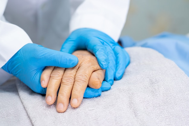 Doctor cogidos de la mano mujer senior asiática con amor y cuidado