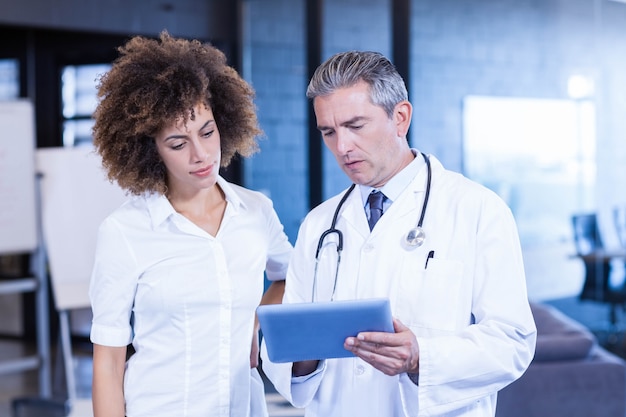 Doctor y colega mirando en tableta digital en hospital