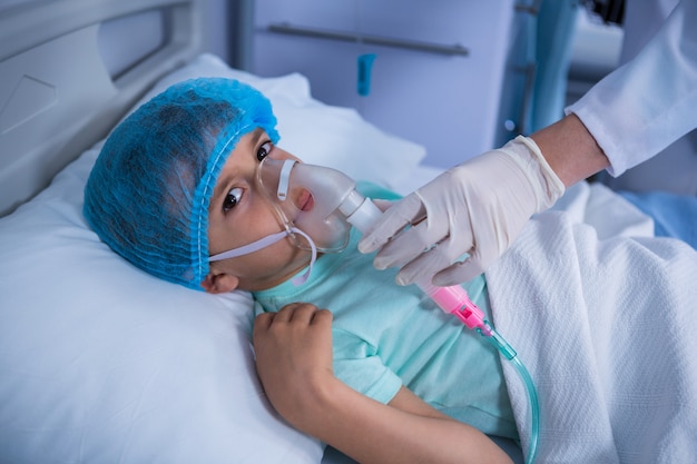 Doctor colocando una máscara de oxígeno en el paciente en sala