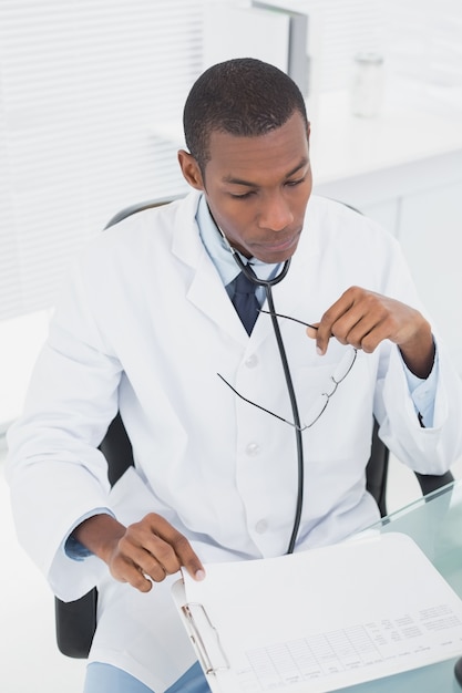 Doctor concentrado leyendo una nota en el consultorio médico