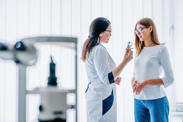 El doctor le da anteojos nuevos al paciente en el interior