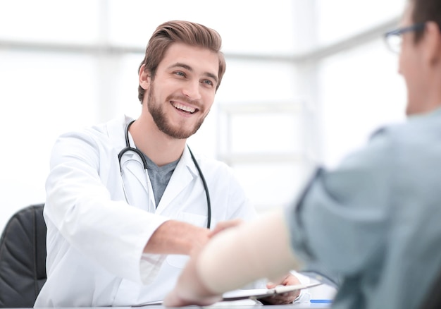 Doctor dando la bienvenida a un paciente en su estudio