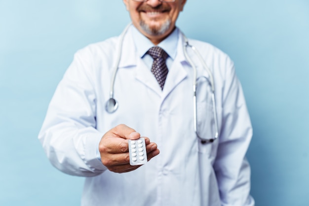 Doctor dando pastillas de medicina. sobre fondo azul El concepto de medicina, farmacología, asistencia sanitaria.