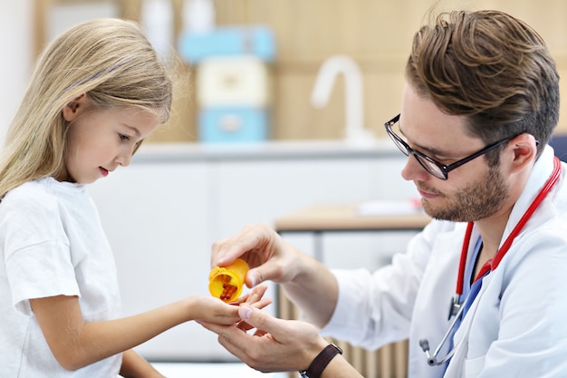 doctor dando pastillas a la niña