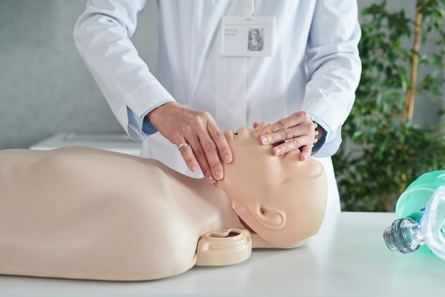 Doctor demostrando respiración artificial en maniquí