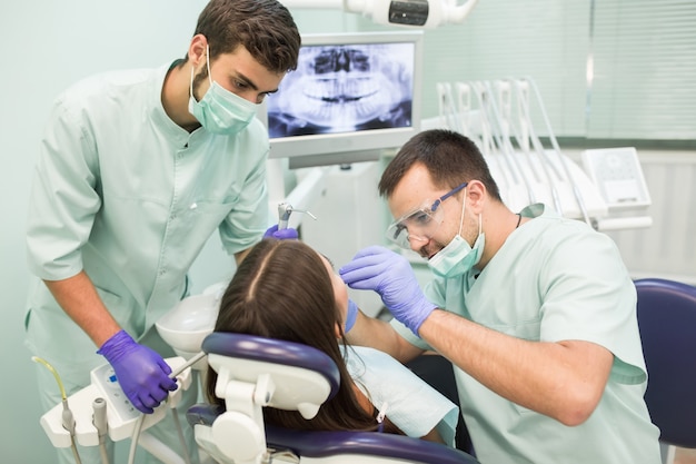 Doctor dentista con un asistente de trabajo en una clínica dental.