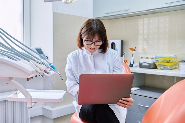 Doctor dentista sentado en la oficina usando una computadora portátil