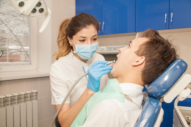 Doctor dentista trata los dientes de los pacientes