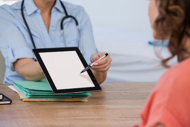 Doctor discutiendo con el paciente sobre tableta digital en el hospital