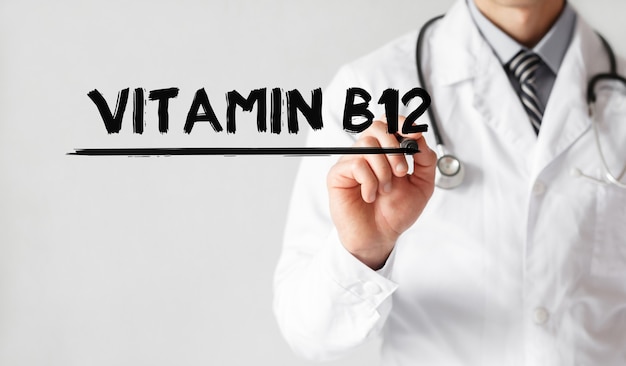 Doctor escribiendo palabra vitamina B12 con marcador, concepto médico