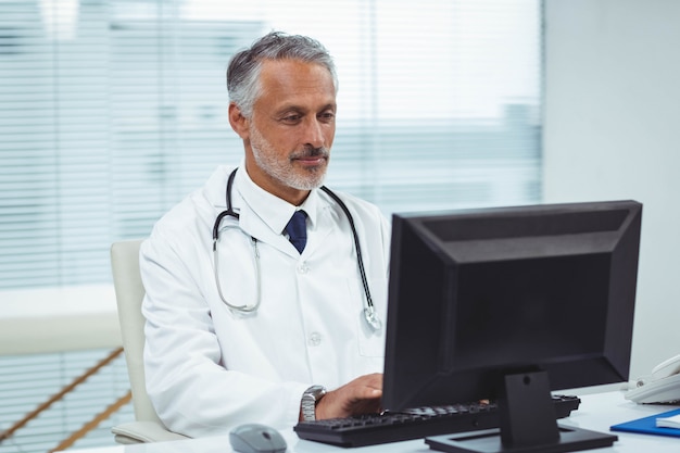 Doctor escribiendo en su computadora en la cabina