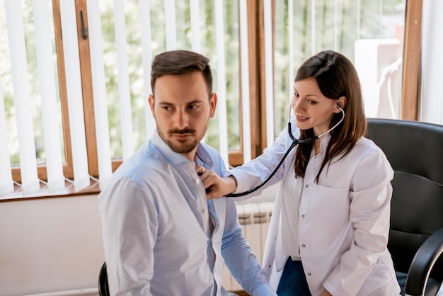 Doctor escuchando el pecho del paciente masculino