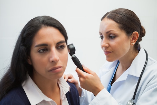 El doctor está mirando en el oído de la mujer