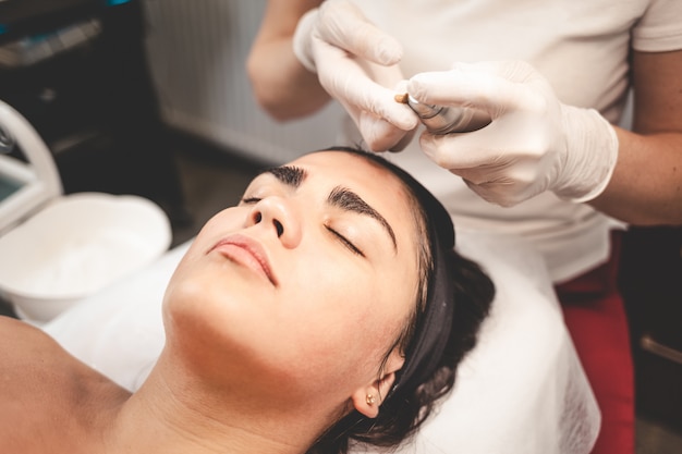 Doctor esteticista aplica aceite en la piel de la cara