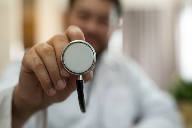 Doctor con estetoscopio en el cheque de la mano a un paciente para la visita médica.