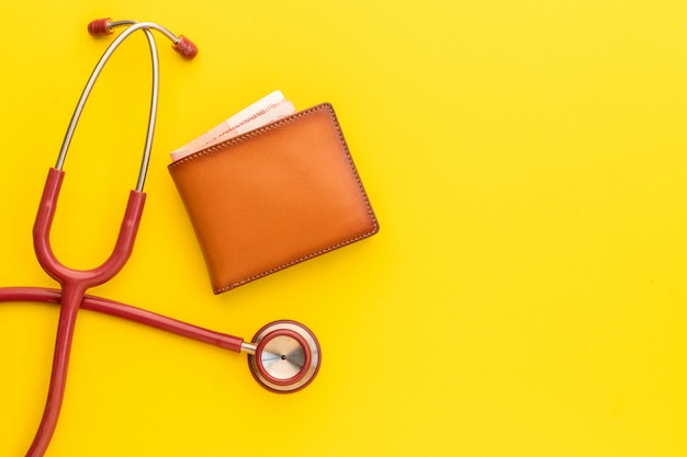 Doctor estetoscopio y la nueva cartera de cuero marrón para hombre en amarillo. Presupuesto para chequeo médico o dinero y concepto financiero