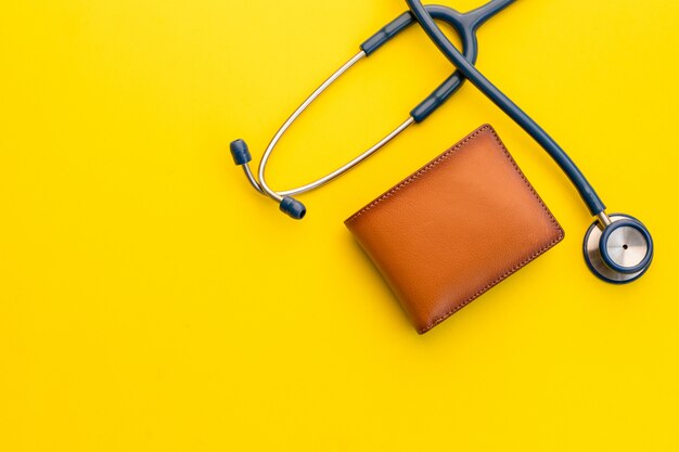 Doctor estetoscopio y la nueva cartera de cuero marrón para hombre en amarillo. Presupuesto para chequeo médico o dinero y concepto financiero