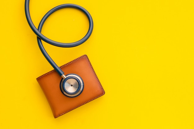 Doctor estetoscopio y la nueva cartera de cuero marrón para hombre en amarillo. Presupuesto para chequeo médico o dinero y concepto financiero