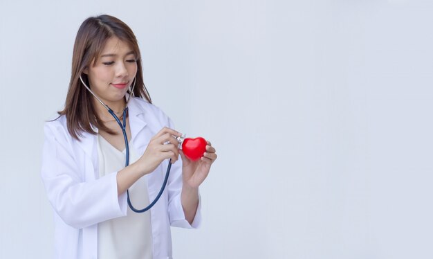 Doctor con el estetoscopio que examina el corazón rojo