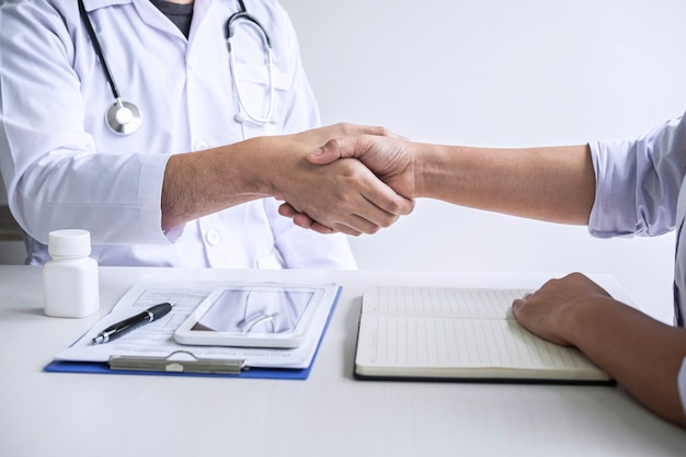 Foto doctor estrechándole la mano a un paciente después de recomendar un tratamiento de enfermedad