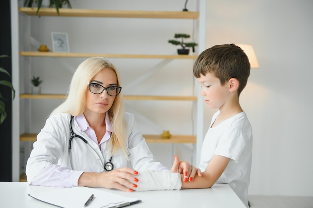 El doctor examina una mano lesionada a un niño pequeño en la oficina