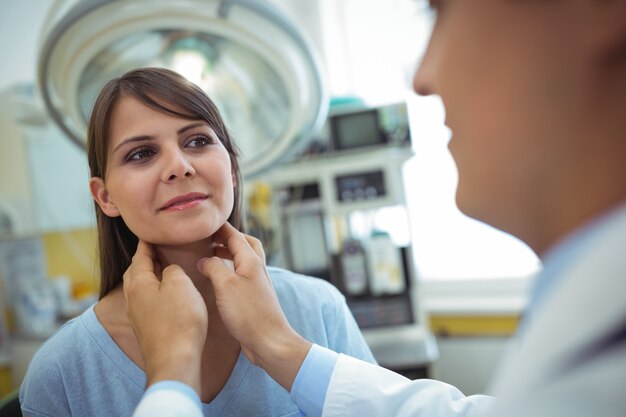 Doctor examinando el cuello de un paciente femenino