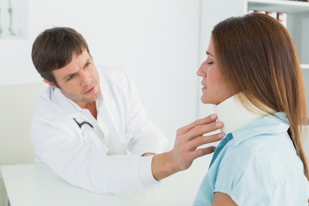 Doctor examinando un cuello de pacientes en consultorio médico