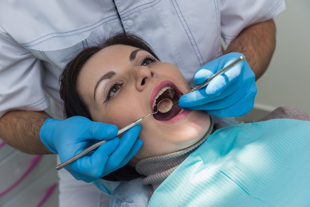 Doctor examinando los dientes de los pacientes con espejo en odontología