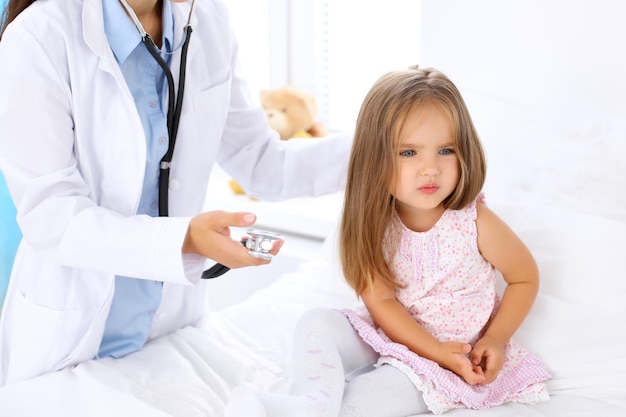 Doctor examinando a una niña con estetoscopio. El paciente se alejó de su médico.