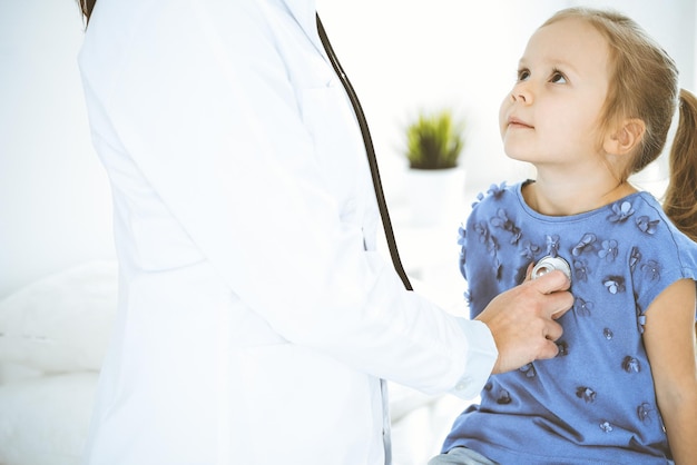 Doctor examinando a una niña con estetoscopio Paciente niño sonriente feliz en la inspección médica habitual Conceptos de medicina y atención médica