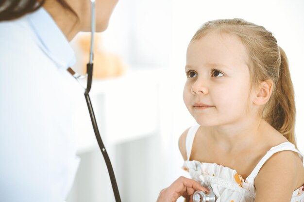 Doctor examinando a una niña con estetoscopio Paciente niño sonriente feliz en la inspección médica habitual Conceptos de medicina y atención médica