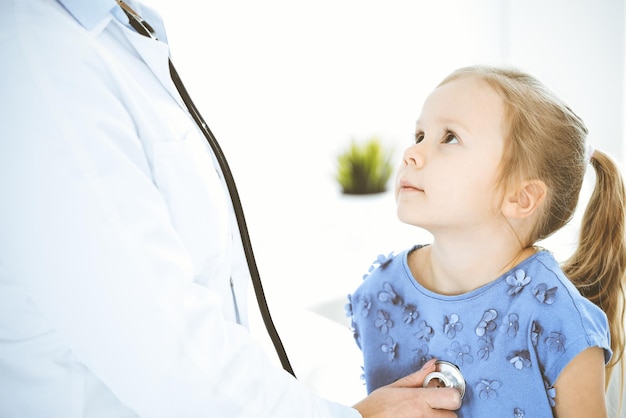 Doctor examinando a una niña con estetoscopio Paciente niño sonriente feliz en la inspección médica habitual Conceptos de medicina y atención médica