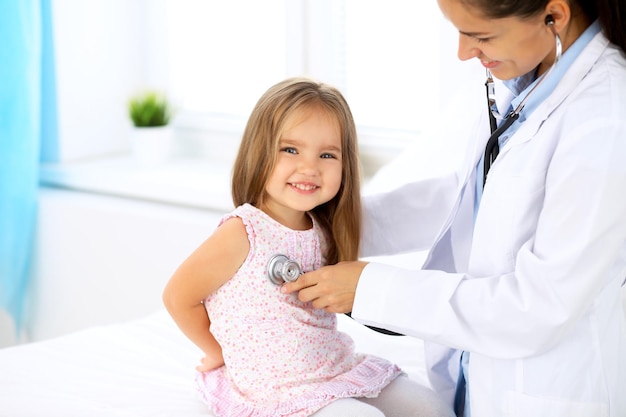 Doctor examinando a una niña con estetoscopio.