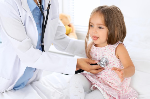 Doctor examinando a una niña con estetoscopio.