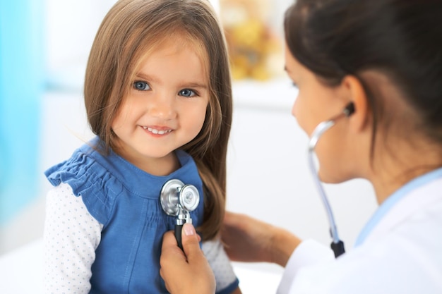 Doctor examinando a una niña con estetoscopio.