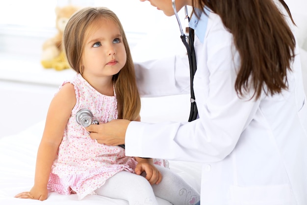 Doctor examinando a una niña con estetoscopio